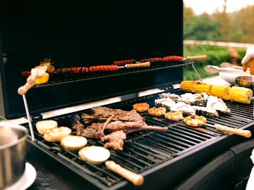 Grill mit verschiedenen Lebensmitteln wird im Freien zubereitet.