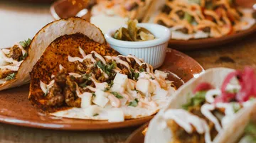 Tacos mit Crema auf braunen Tellern.