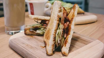 Toasted sandwich with lettuce on wooden board.