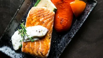 Grilled salmon with sauce, tomato, and zucchini.