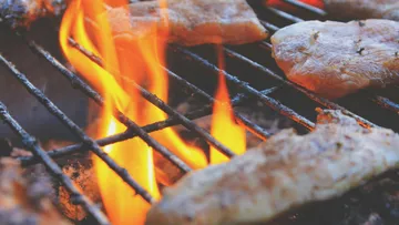 Gegrilltes Fleisch, das auf offener Flamme zubereitet wird.