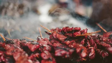 Gegrilltes Fleisch am Spieß mit rauchigem Hintergrund.