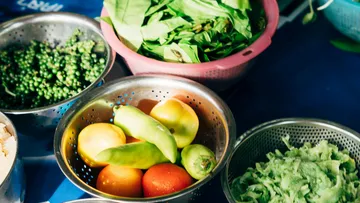 Vegetables in colanders on a table.