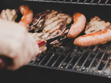 Würste werden auf einem Grill gewendet, draußen gegrillt.