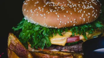 Cheeseburger with lettuce, tomato, and potato wedges.