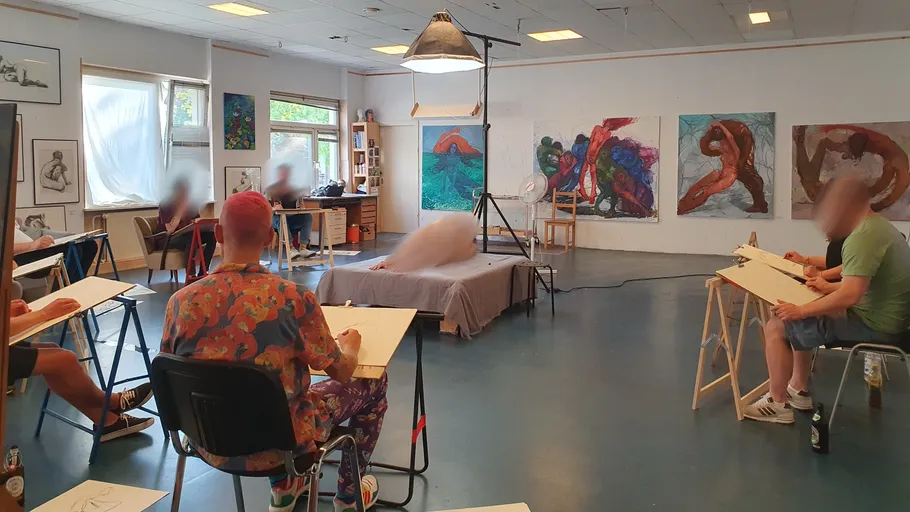 Art students sketch a live model in a studio.