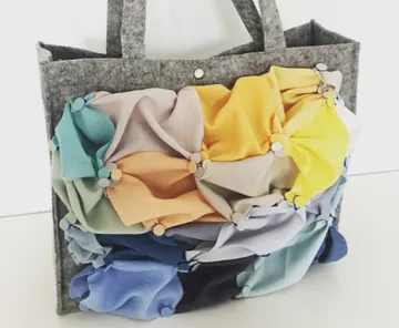 Multicolored fabric bag with gray handles.