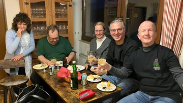 Five people sitting around a table, smiling.