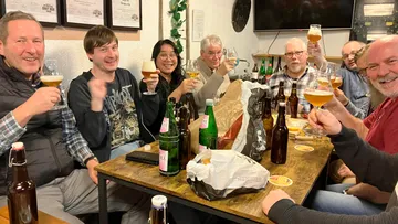 Group of people toasting with beers indoors.