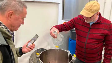 Two men brew beer in a brewery.