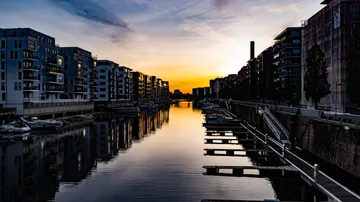 Kanal mit Gebäuden, die bei Sonnenuntergang silhouettiert sind.
