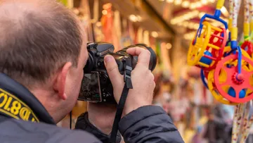 Mann fotografiert buntes Spielzeug auf dem Markt