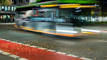 Blurred bus speeding through city street at night.