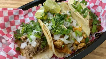 Three tacos with cilantro and lime slices.