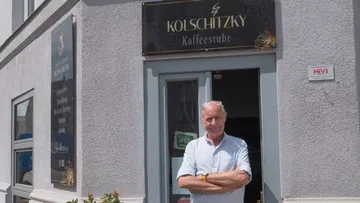 Man stands outside Kolschitzky Kaffestube entrance.