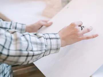 A hand draws on a blank sheet of paper.