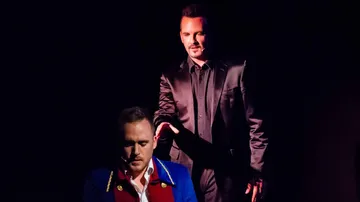 Two men in dramatic stage lighting.