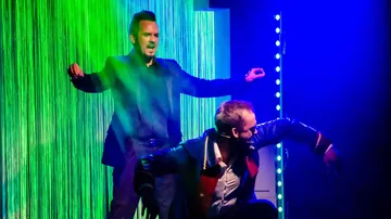 Two performers on stage, dramatic lighting effects.