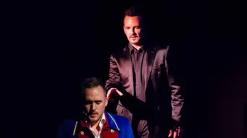 Two men performing in dramatic stage lighting.