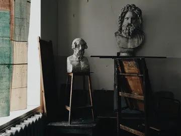Statues stand on pedestals in an artistic space.