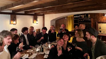 Gruppe von Menschen, die Getränke in einem gemütlichen Holzraum genießen.