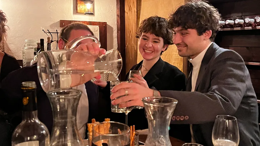 Leute, die Getränke an einem Esstisch einschenken.