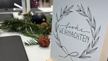 Christmas card with wreath design on table.