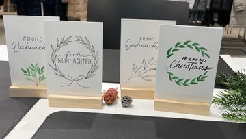 Four Christmas cards on stands with festive designs.
