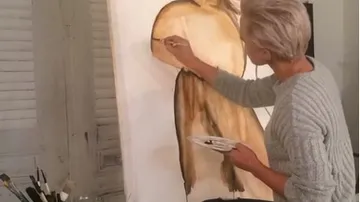 Artist painting on canvas in studio.