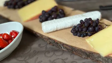 Käse und Trauben auf Holzbrett.