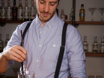 Bartender stirs a drink in a bottled bar.