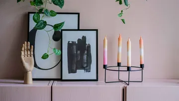 Dekorative Kerzen, gerahmte Kunst, Holzhand auf dem Regal.