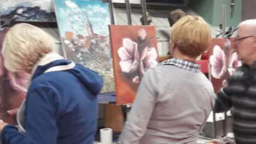 People painting floral artworks in a studio.
