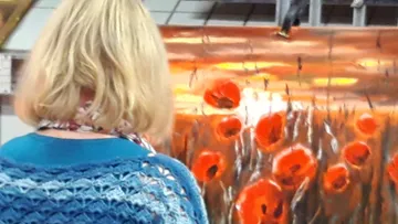Person, die Kunstwerke von Mohnfeldern beobachtet.