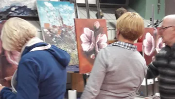 People painting floral art in a studio