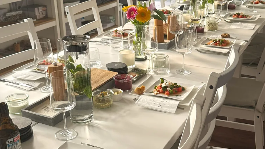 Dining table set with plates, glasses, and flowers.