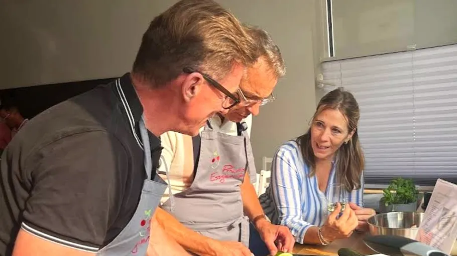 Three people cooking together in kitchen.
