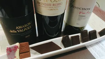 Three wine bottles with assorted chocolates on tray.