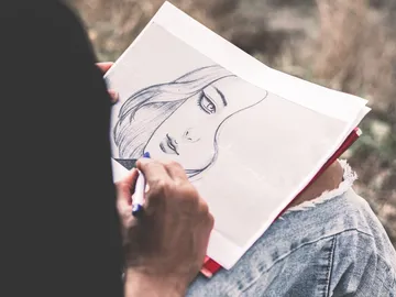 Drawing of a face is sketched by a person.
