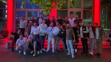 Gruppe von Menschen, die draußen unter roten Lichtern posieren.
