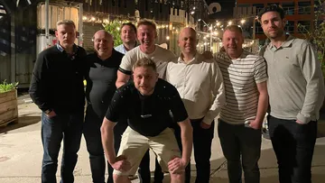Gruppe von Männern, die nachts draußen lächeln.