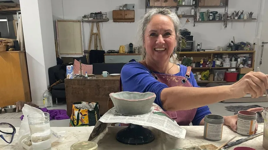 Woman painting pottery in a studio.