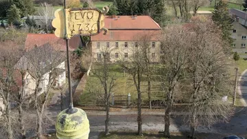 Weather vane with '1736' over estate grounds.