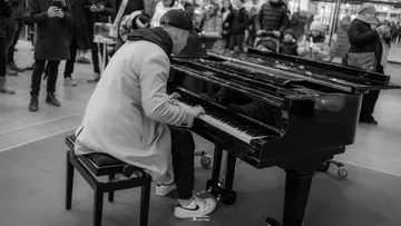 Person, die im belebten öffentlichen Raum Klavier spielt.