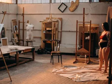 A naked figure stands on a towel in the studio.