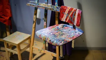 Mit Farbe bespritzter Stuhl und Staffelei im Studio.