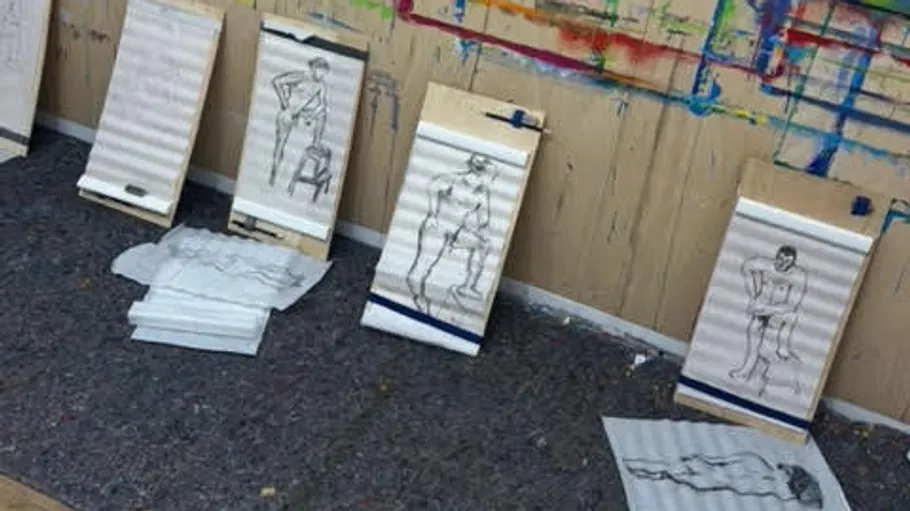 Figurenskizzen auf Papier, die entlang einer Wand angeordnet sind.