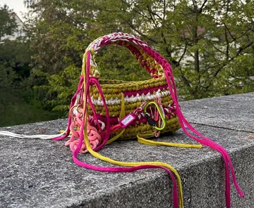Mehrfarbige gewebte Handtasche auf einem Steinsims im Freien.