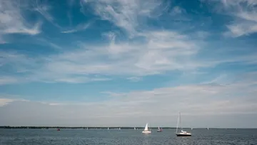Sailboats on calm water under blue sky.