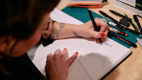Person drawing on paper with markers.